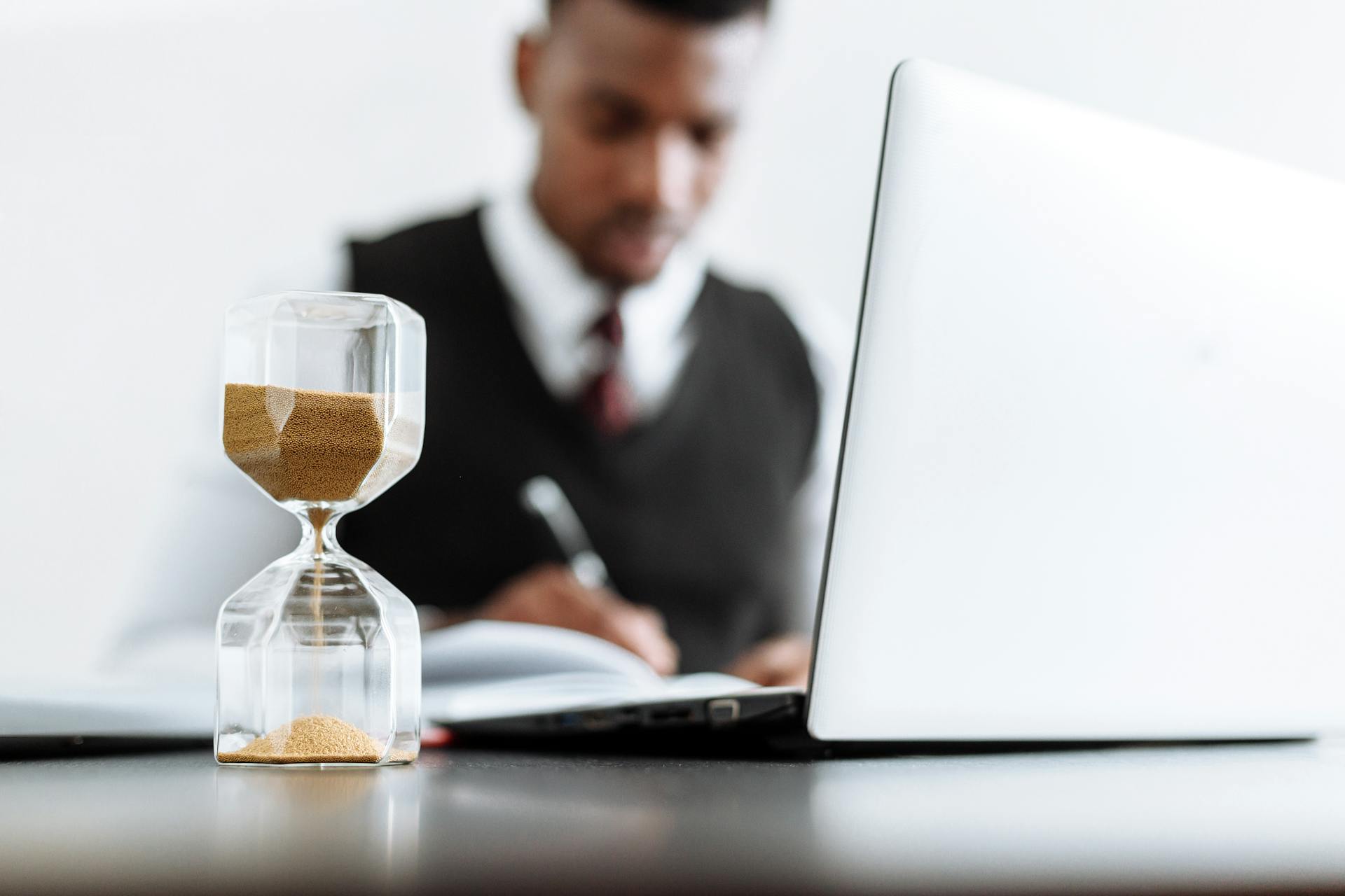 man on laptop with an hourglass on the desk