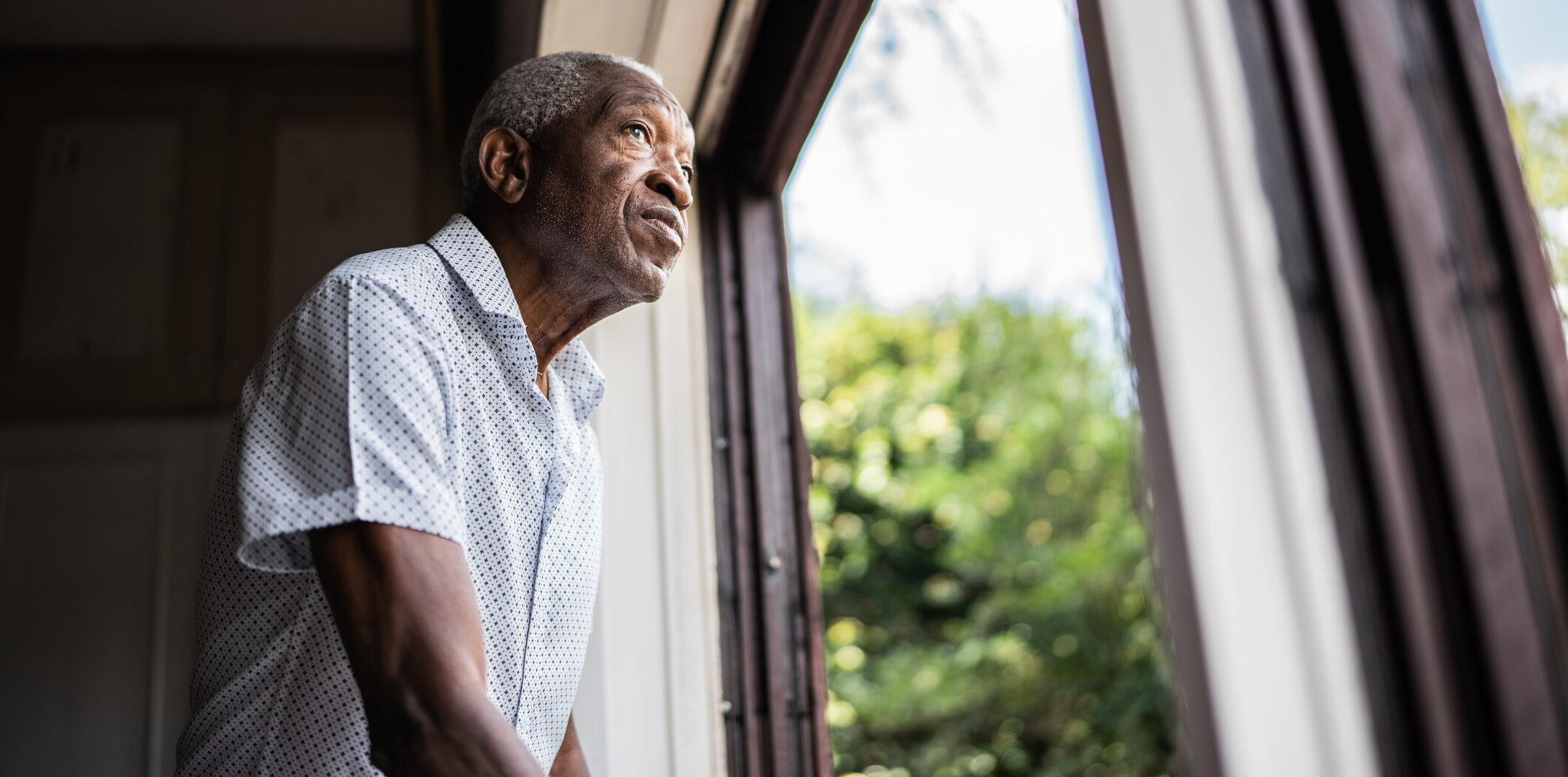 Senior man contemplating looking through the window