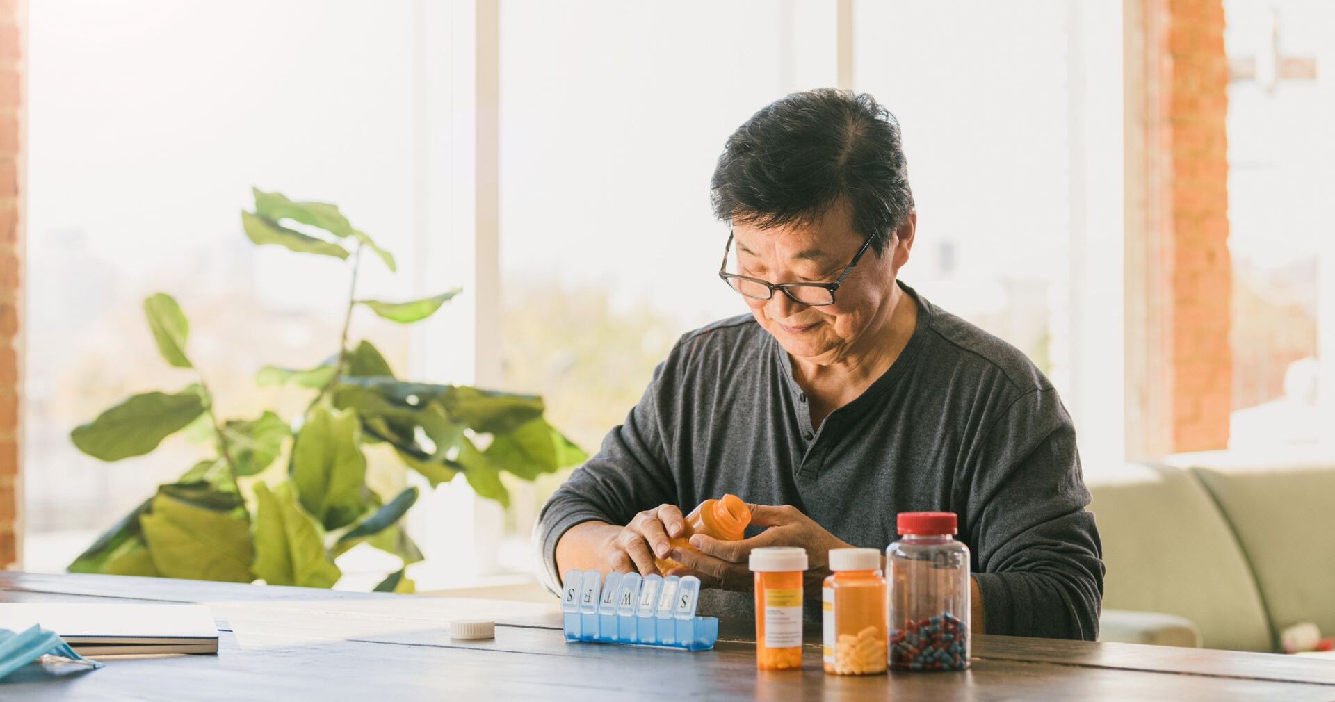 Elderly widower organizing pills for the week at home